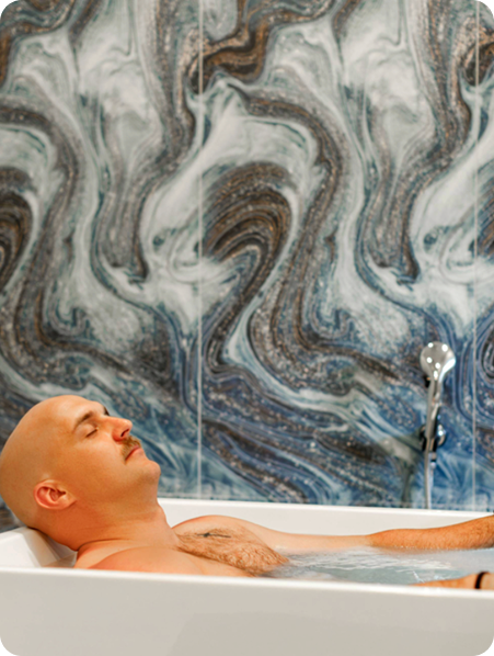 - The Renaissance Day Spa & Alternative Wellness, Fayetteville NC A bald man with a mustache relaxes in a bathtub filled with water, surrounded by a marble-patterned wall, enjoying luxury day spa packages for ultimate relaxation. - The Renaissance Day Spa & Alternative Wellness, Fayetteville NC