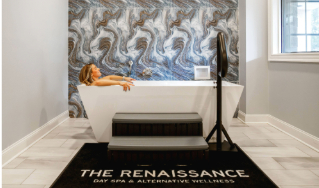 - The Renaissance Day Spa & Alternative Wellness, Fayetteville NC A person relaxes in a modern white bathtub against a marbled accent wall, with a mat reading “The Renaissance Day Spa & Alternative Wellness” in the foreground. - The Renaissance Day Spa & Alternative Wellness, Fayetteville NC