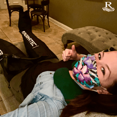- The Renaissance Day Spa & Alternative Wellness, Fayetteville NC Woman lying on a lounge chair indoors, wearing patterned face mask and compression pants, giving a thumbs up. The room has tile flooring and wooden chairs. - The Renaissance Day Spa & Alternative Wellness, Fayetteville NC