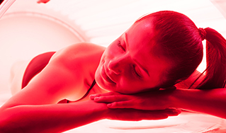 - The Renaissance Day Spa & Alternative Wellness, Fayetteville NC A woman lies inside a tanning bed, resting her head on her arms and appearing relaxed under red-tinted light. - The Renaissance Day Spa & Alternative Wellness, Fayetteville NC
